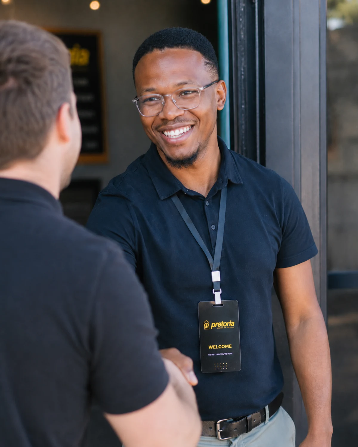 A host welcoming a visitor with a handshake at the door